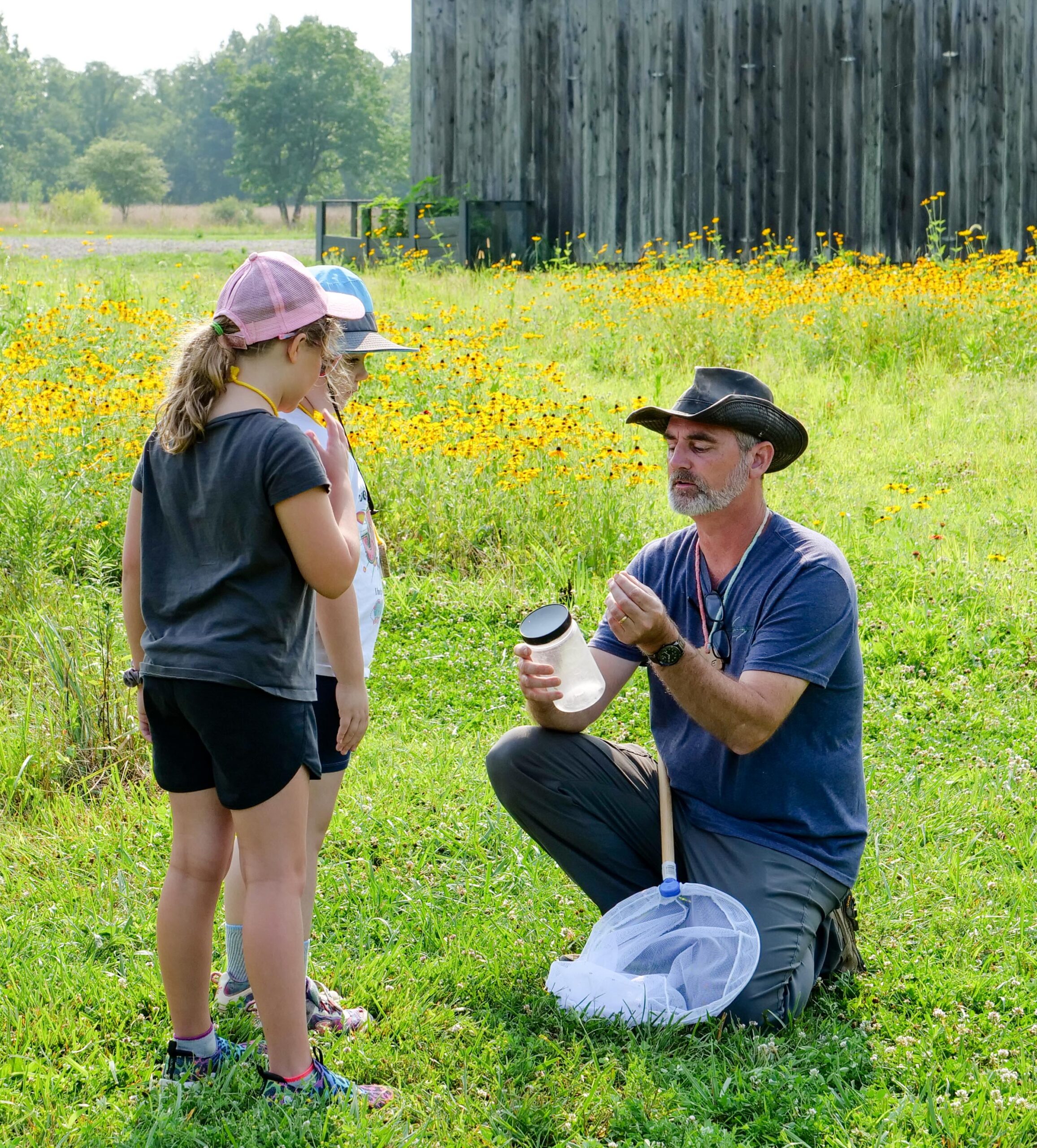 Greenacres educator and Lewis Township site supervisor, Joe Phelps teaching two young students about bugs in the field